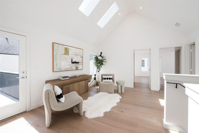 sitting room featuring a skylight, high vaulted ceiling, and light wood-type flooring