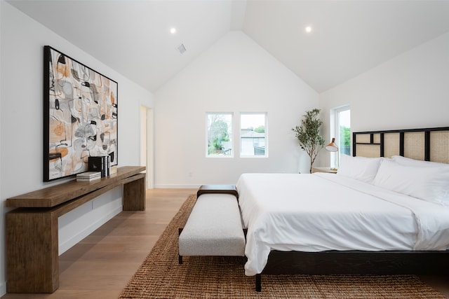 bedroom with high vaulted ceiling and light wood-type flooring