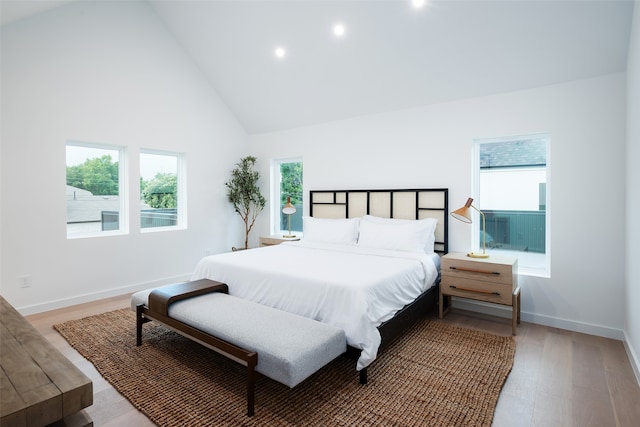 bedroom with wood-type flooring and high vaulted ceiling