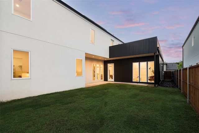 back house at dusk with a lawn