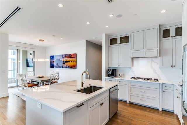 kitchen featuring light hardwood / wood-style floors, light stone countertops, a kitchen island with sink, sink, and stainless steel appliances