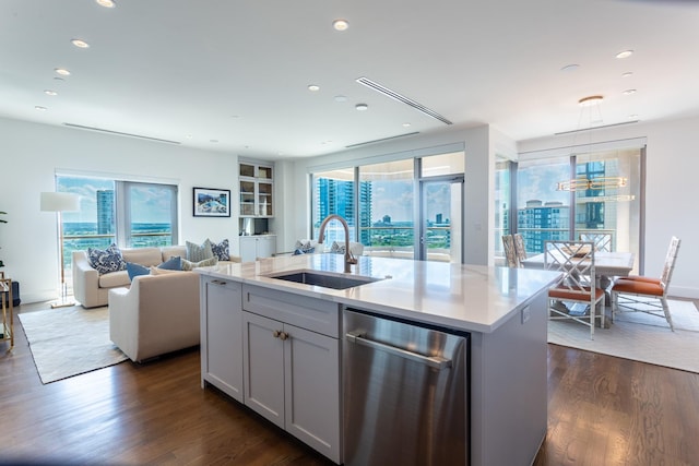 kitchen featuring dishwasher, sink, decorative light fixtures, dark hardwood / wood-style flooring, and an island with sink