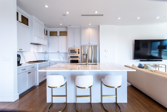 kitchen with an island with sink, white cabinetry, appliances with stainless steel finishes, and dark hardwood / wood-style flooring