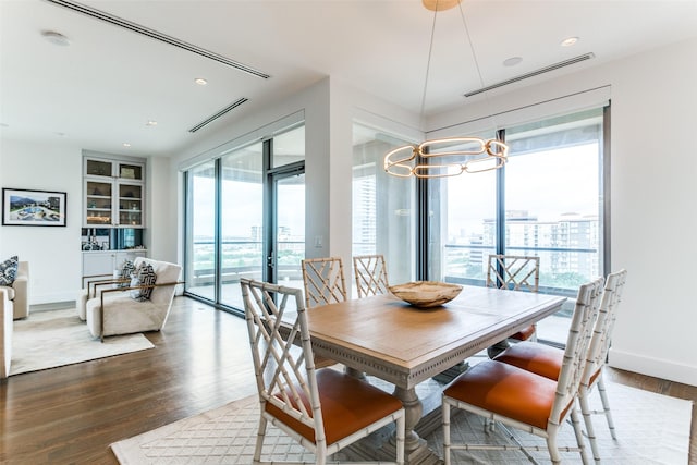 dining space with a healthy amount of sunlight, an inviting chandelier, and wood-type flooring