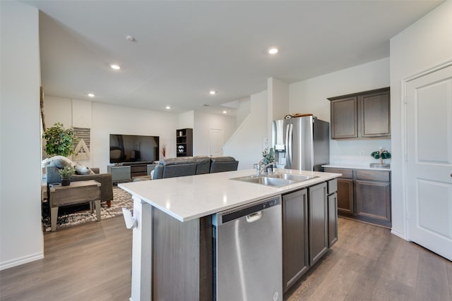 kitchen featuring stainless steel appliances, sink, an island with sink, dark brown cabinets, and dark hardwood / wood-style flooring