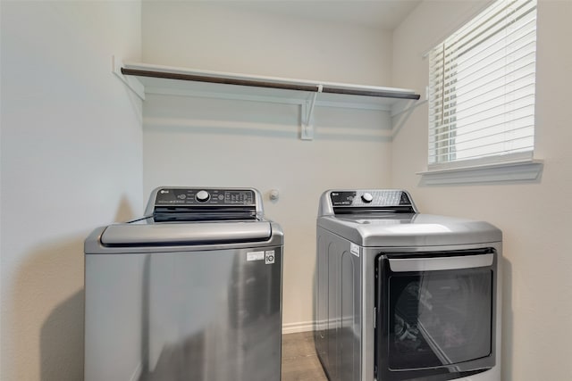 clothes washing area with washing machine and dryer and hardwood / wood-style flooring