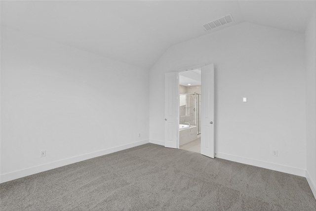 carpeted empty room with vaulted ceiling