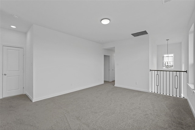 spare room featuring carpet floors and a notable chandelier