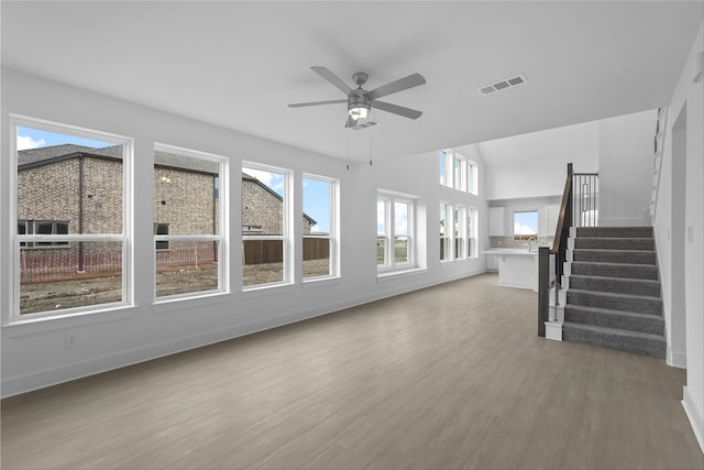 unfurnished living room featuring ceiling fan, plenty of natural light, and wood-type flooring