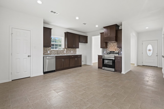 kitchen with backsplash, dark brown cabinets, custom range hood, and appliances with stainless steel finishes