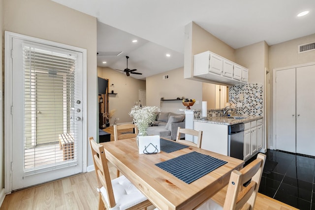 dining room featuring ceiling fan, vaulted ceiling, sink, and light wood-type flooring