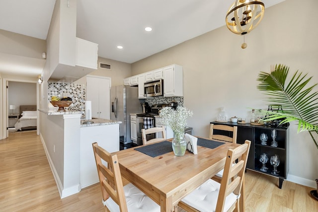 dining area featuring light hardwood / wood-style floors and an inviting chandelier