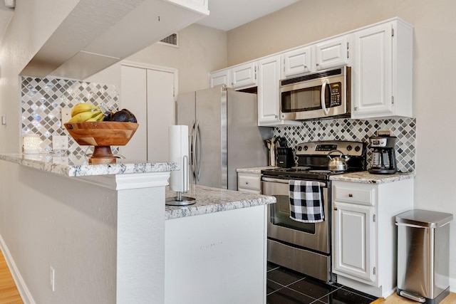 kitchen featuring decorative backsplash, light stone countertops, white cabinetry, and stainless steel appliances