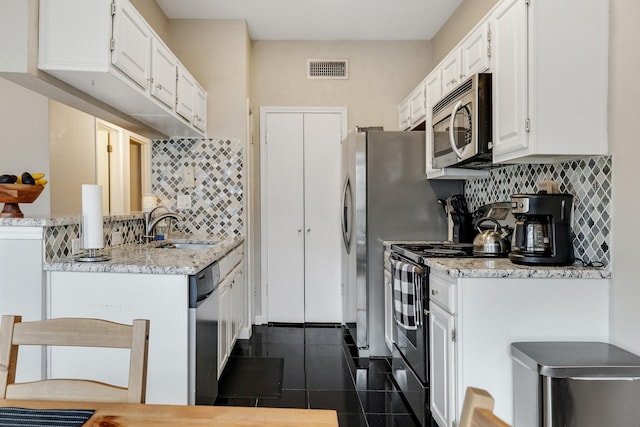 kitchen with backsplash, sink, light stone countertops, stainless steel appliances, and white cabinets