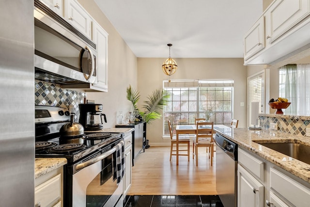 kitchen featuring white cabinets, appliances with stainless steel finishes, and pendant lighting