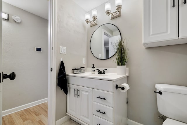 bathroom featuring toilet, hardwood / wood-style flooring, and vanity