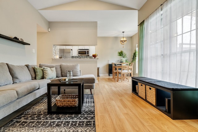 living room featuring hardwood / wood-style floors, a chandelier, and vaulted ceiling