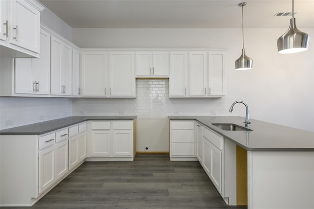 kitchen featuring tasteful backsplash, white cabinetry, sink, and decorative light fixtures