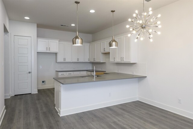 kitchen featuring backsplash, kitchen peninsula, white cabinetry, and sink