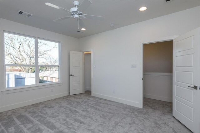 unfurnished bedroom featuring a closet, light colored carpet, and ceiling fan