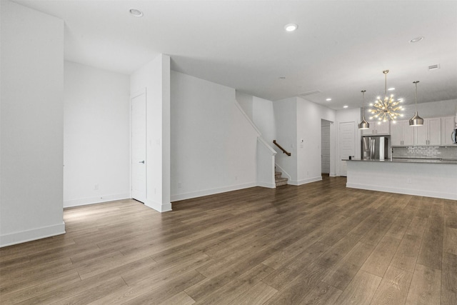 unfurnished living room featuring recessed lighting, stairs, wood finished floors, and an inviting chandelier