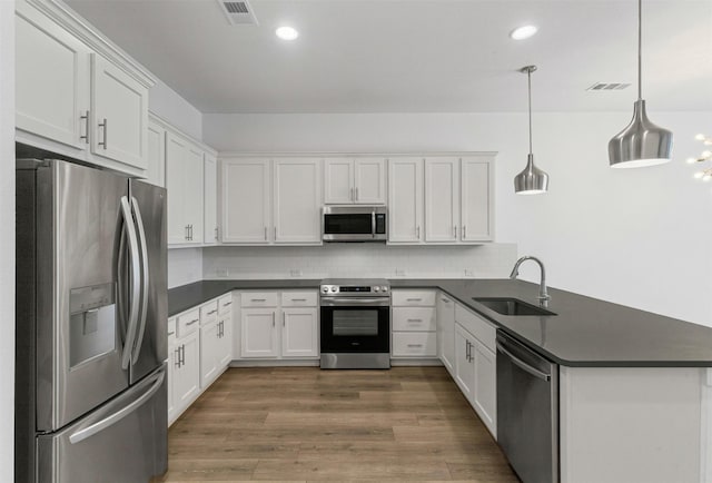 kitchen featuring visible vents, a sink, dark countertops, and stainless steel appliances