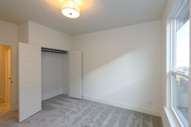 unfurnished bedroom with a closet and light colored carpet