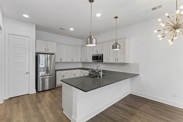 kitchen featuring a peninsula, dark countertops, appliances with stainless steel finishes, and tasteful backsplash