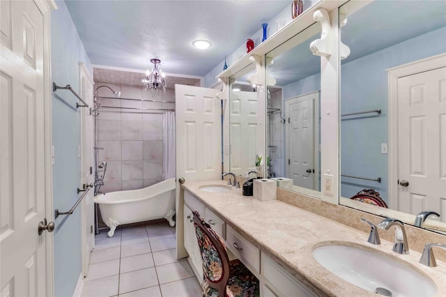 full bathroom with double vanity, a freestanding bath, a sink, and tile patterned floors