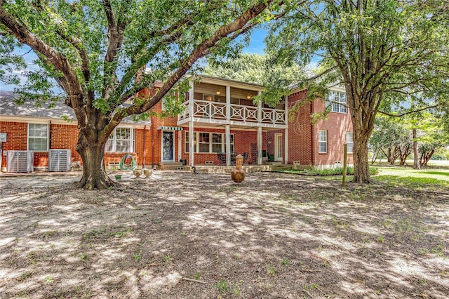 view of front of property featuring cooling unit, brick siding, and a balcony