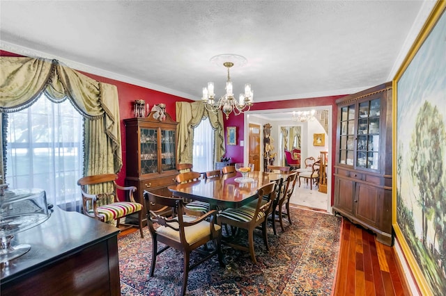 dining room with a healthy amount of sunlight, ornamental molding, dark wood-style flooring, and a notable chandelier