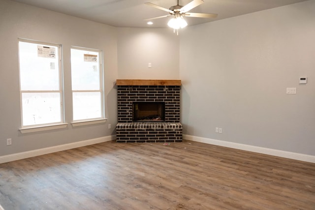 unfurnished living room with a brick fireplace, ceiling fan, and hardwood / wood-style flooring