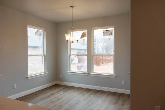 unfurnished dining area featuring a notable chandelier, hardwood / wood-style floors, and a healthy amount of sunlight