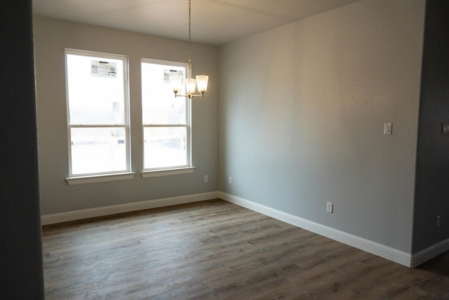 unfurnished dining area featuring an inviting chandelier and hardwood / wood-style flooring