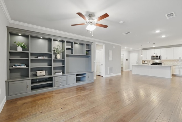 unfurnished living room with ornamental molding, light wood finished floors, and visible vents