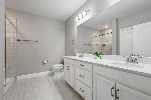 full bathroom featuring a stall shower, a sink, baseboards, and double vanity