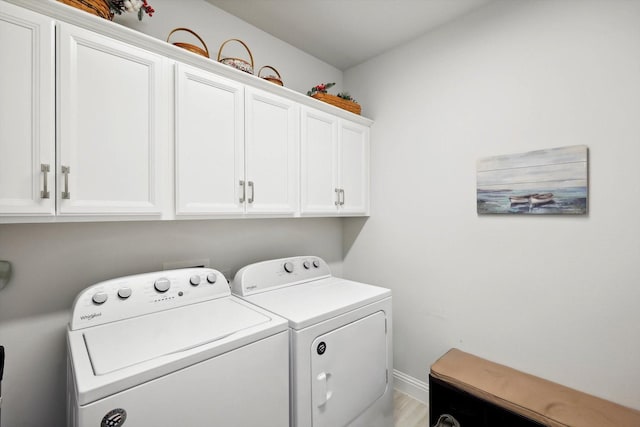 laundry area with light wood-type flooring, cabinets, and washer and dryer