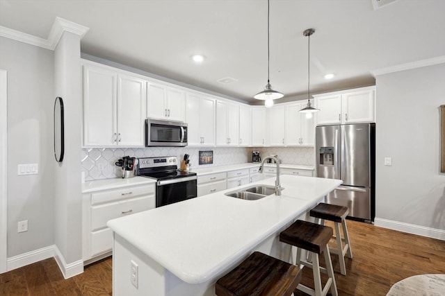 kitchen with white cabinetry, stainless steel appliances, an island with sink, sink, and hanging light fixtures