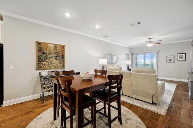 dining area featuring dark wood-type flooring, ceiling fan, and crown molding