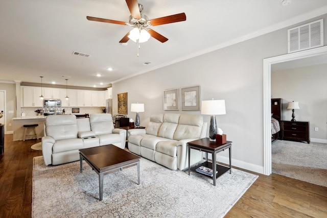 living room featuring ceiling fan, light hardwood / wood-style flooring, and crown molding