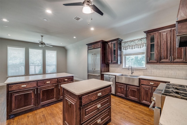 kitchen with stainless steel appliances, light hardwood / wood-style floors, sink, and a kitchen island