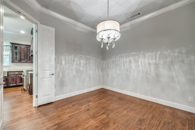 empty room featuring ornamental molding, wood-type flooring, and a notable chandelier