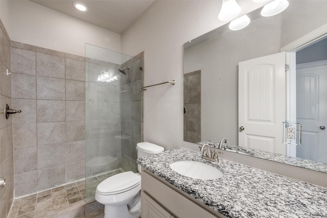 bathroom featuring vanity, tiled shower, and toilet