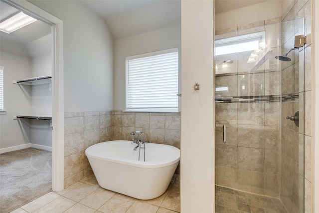 bathroom with independent shower and bath, tile patterned flooring, and tile walls