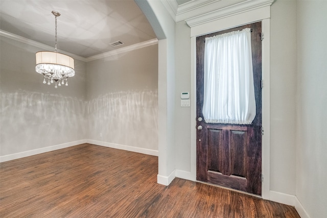 foyer with dark hardwood / wood-style floors, crown molding, and a chandelier