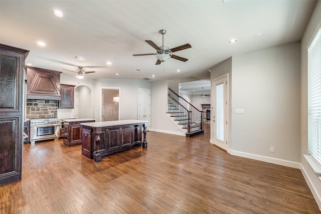 kitchen with dark hardwood / wood-style floors, high end range, custom exhaust hood, a center island, and dark brown cabinetry