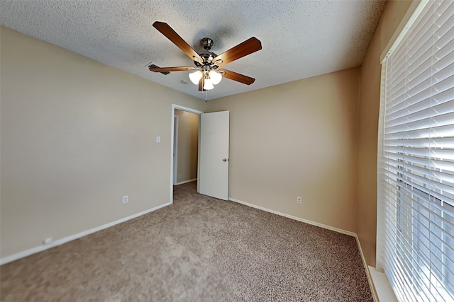 empty room featuring carpet floors, a healthy amount of sunlight, ceiling fan, and a textured ceiling