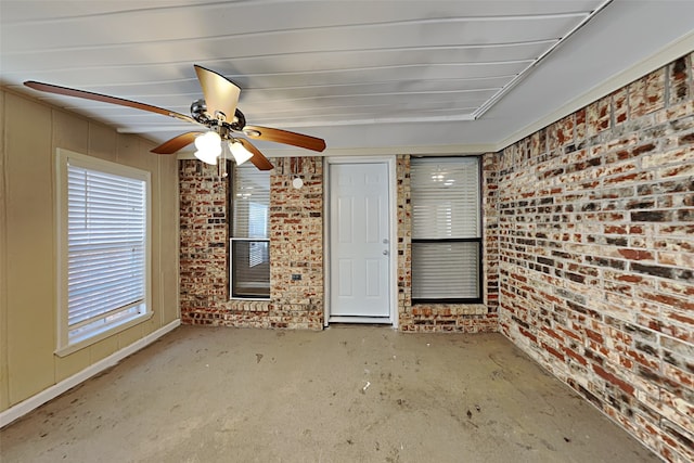 interior space featuring ceiling fan and brick wall