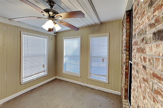 unfurnished room featuring ceiling fan and brick wall