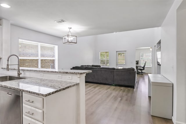 kitchen featuring white cabinets, pendant lighting, sink, dishwasher, and light hardwood / wood-style flooring